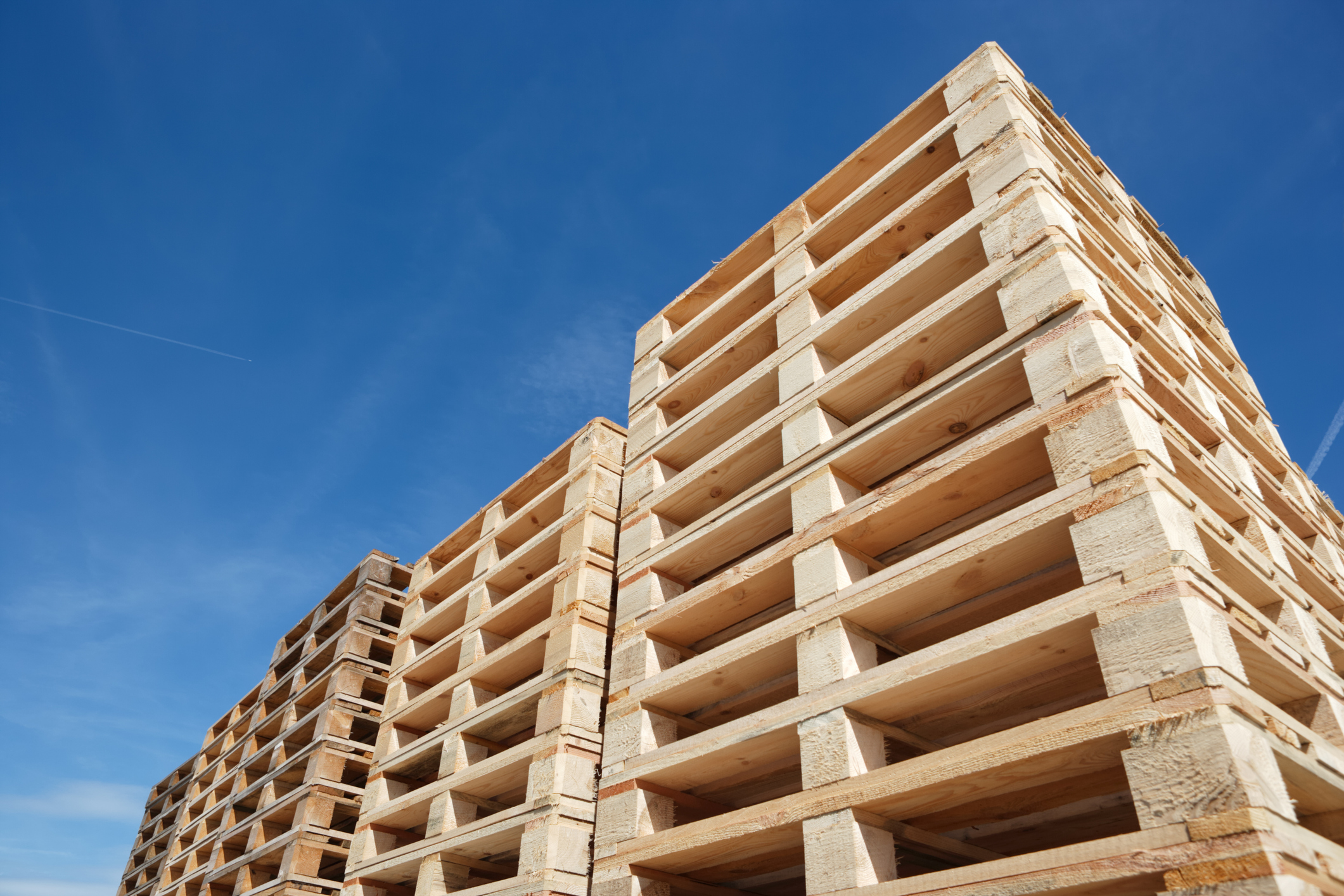stack of wooden pallets against clear blue sky, low angle view